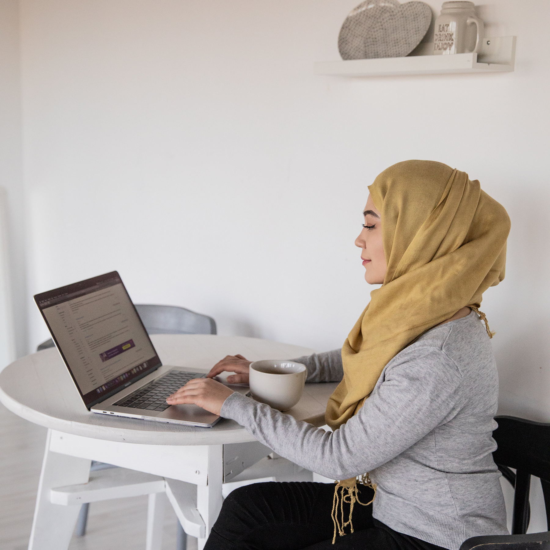 Woman sitting at the table with her laptop navigating the internet.